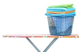 A laundry basket full of clothes on ironing board isolated on wh